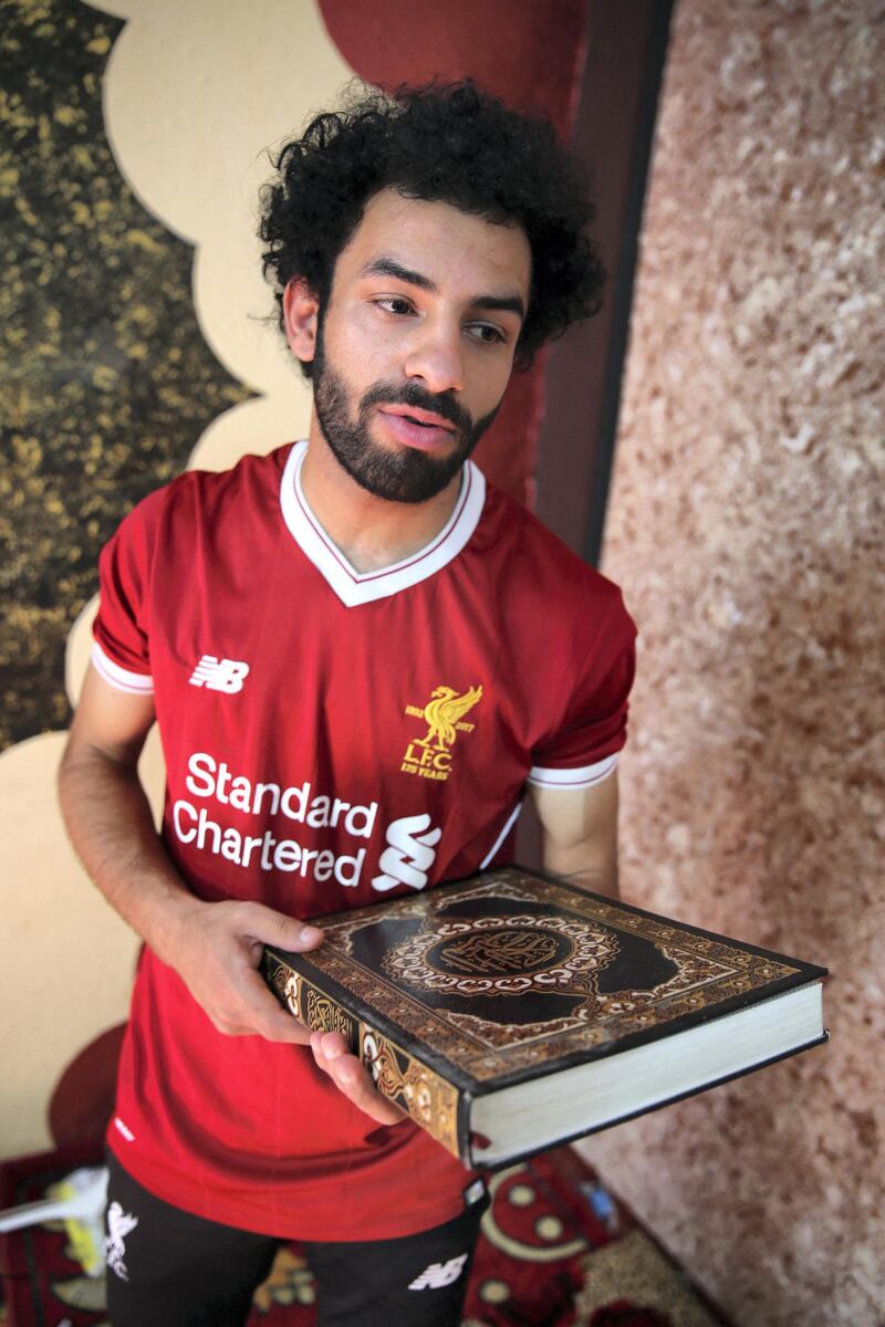 Iraqi footballer Hussein Ali, who plays for the Iraqi Al-Zawraa FC and is a lookalike of Liverpool's Egyptian forward Mohamed Salah, carries a copy of the Koran, Islam's Holy book, in the capital Baghdad, on June 4, 2018. - With his black beard, curly hair and football shirt, Iraqi striker Hussein Ali is often mistaken for one of the world's top players: Egypt's Mohamed Salah. (Photo by SABAH ARAR / AFP)