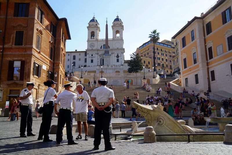 Local police stand near the 17th century fountain, called "Barcaccia" (Sunken Boat) on August 12, 2017 at the bottom of the Spanish Steps in Rome. A ban on frolicking in the city's historic fountains is repeatedly flouted by tourists desperate to cool off during the hot summer days.  / AFP PHOTO / Marie-Laure MESSANA