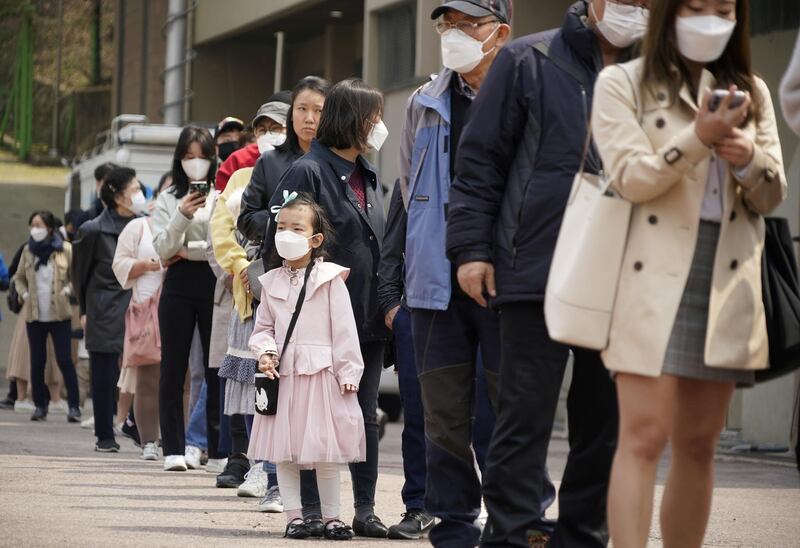 People wearing masks wait in line to cast their ballots at a polling station in Seoul, South Korea. Reuters