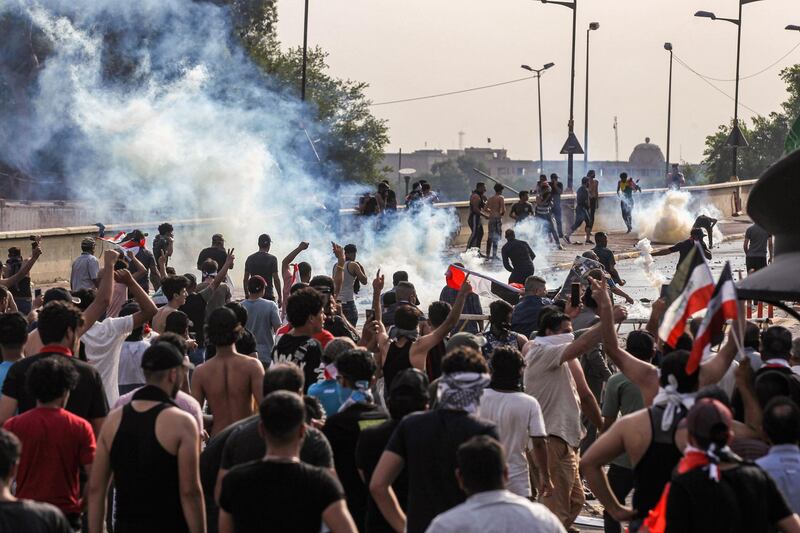 Protesters stand amid tear gas fumes as they clash with Iraqi riot police between the capital Baghdad's Tahrir Square and the high-security Green Zone district. AFP