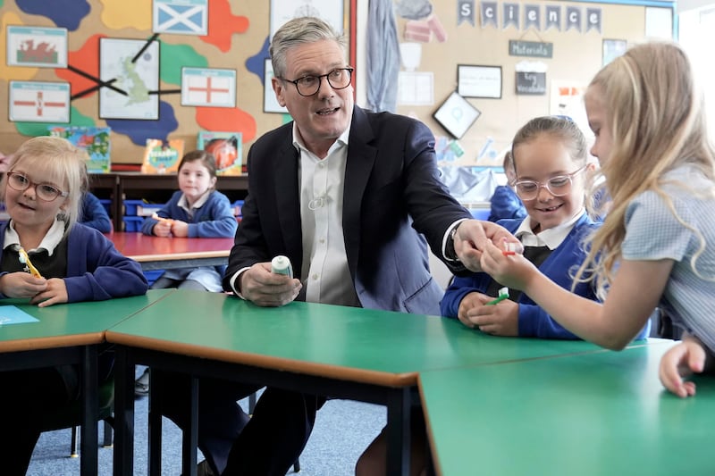 Mr Starmer passes a toothbrush to a child during his visits to the Whale Hill Primary School in Middlesbrough. AP