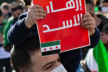 A child holds a sign that reads 'Stop the terrorism of Assad ' as Syrians in Istanbul rally to mark the 10th anniversary of the start of the war. AFP 