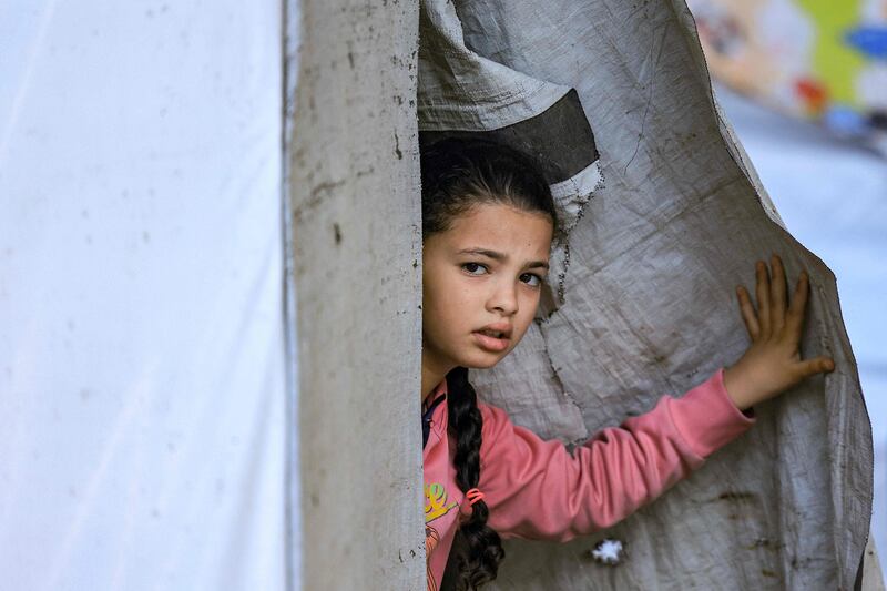 A young girl peeks through the entrance of a tent. AFP