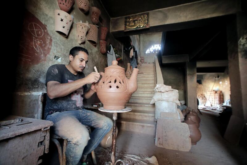 An Egyptian worker shapes a clay ornament at a pottery workshop.