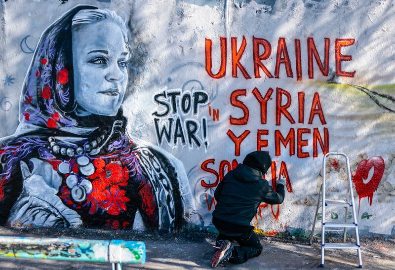Colombian street artist Arte Vilu works on a mural featuring a Ukrainian woman in traditional dress in Berlin, Germany. AP