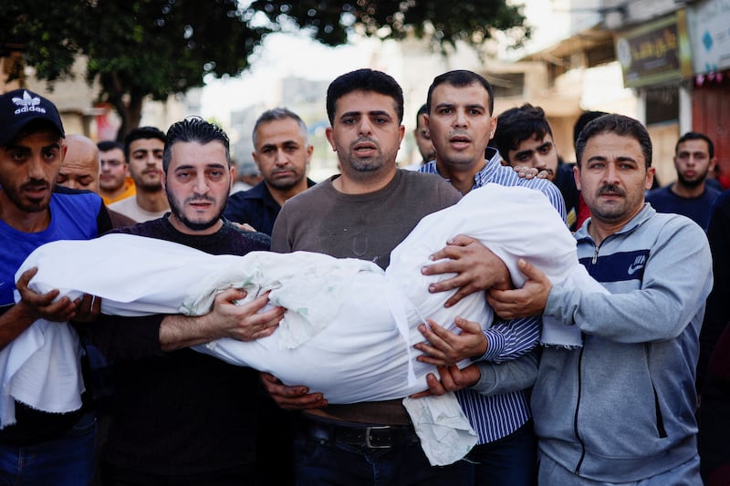 The father of Palestinian girl Lianne Mdoukh, who was killed in Israel-Gaza fighting, carries her body during the funeral in Gaza. Reuters