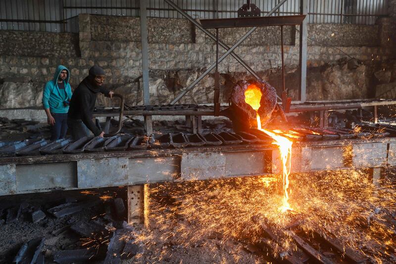 Labourers at a factory recycling war remnants and scrap metal near the Bab al-Hawa crossing between Syria and Turkey. AFP

