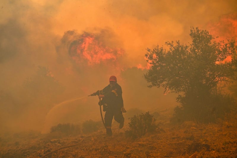 A fireman tries to control a wildfire in New Peramos, near Athens, Greece. AFP