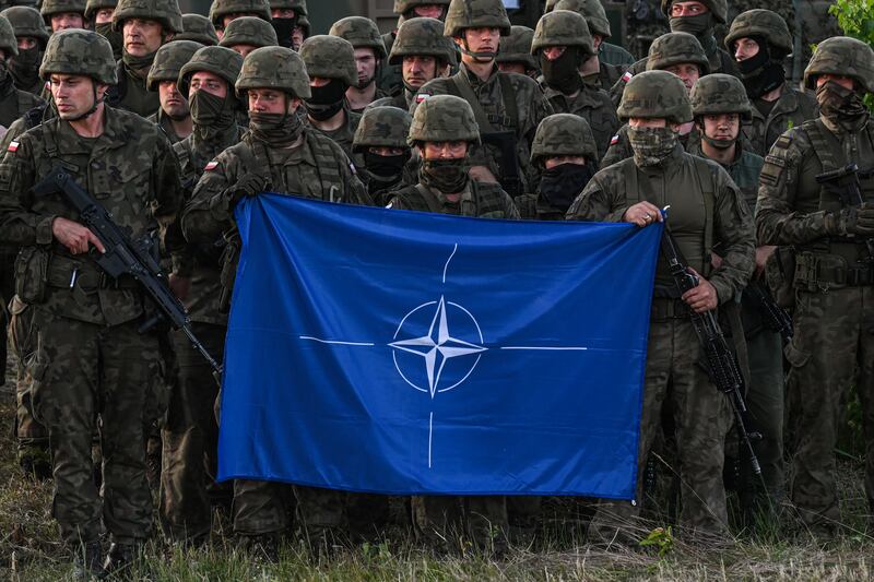 Polish soldiers hold a Nato flag in 2022 at a training ground in Orzysz, Poland