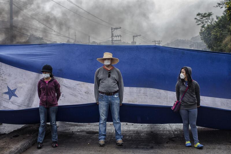 Protesters hold a Honduran flag as they block a road during protests against the presidential election of Juan Orlando Hernandez in Tegucigalpa, Honduras. Juan Carlos / Bloomberg