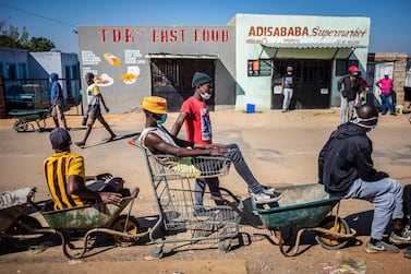 Wheelbarrow couriers wait to take food from a supply centre in Johannesburg to customers on day 40 of the South African lockdown. EPA