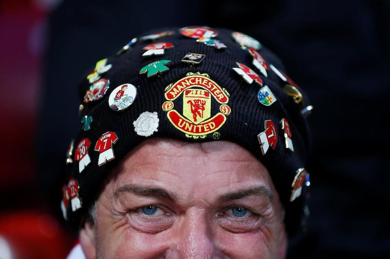 AManchester United fan has plenty of badges on his hat. Action Images via Reuters