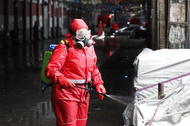 A Syrian Red Crescent member sprays disinfectant along an alley of the historic Hamidiyah souk (market) in the old city of Syria's capital Damascus on March 22, 2020, as part of efforts against the COVID-19 coronavirus pandemic.  / AFP / LOUAI BESHARA
