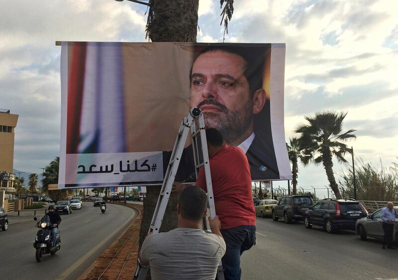 Workers hang a poster of outgoing Prime Minister Saad Hariri with Arabic words that read, "We are all Saad," at a seaside street in Beirut, Lebanon, Thursday, Nov. 9, 2017. Hezbollah has called on Saudi Arabia to stay out of Lebanese affairs, saying the resignation of Prime Minister Saad Hariri, announced from Riyadh over the weekend, "has raised many questions." (AP Photo/Hussein Malla)