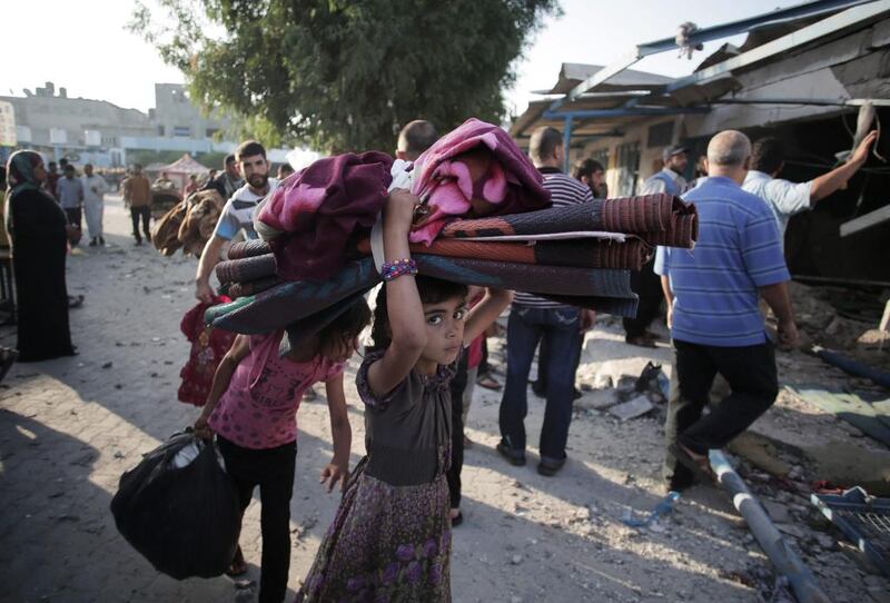 A Palestinian girl carries belongings as she and her family leave the Abu Hussein U.N. school in the Jebaliya refugee camp, northern Gaza Strip, hit by an Israeli strike. Khalil Hamra / AP Photo