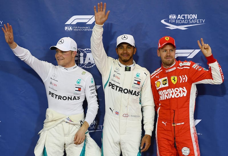Hamilton celebrates after taking the pole position next to Ferrari's German driver Sebastian Vettel (right, third place) and Mercedes' Finnish driver Valtteri Bottas (left, second place). AFP