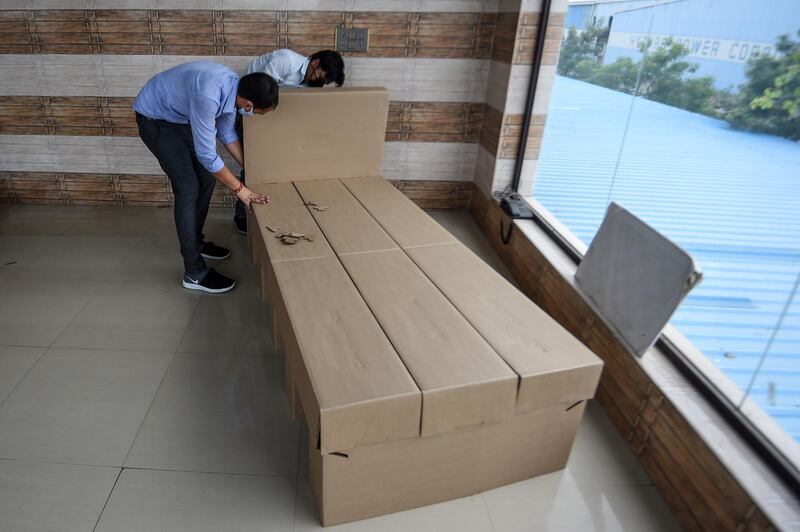 Workers demonstrating how to arrange a cardboard bed at a factory in which cardboard beds are made for COVID-19 coronavirus patients at Bhiwadi in the state of Rajasthan. India is deploying thousands of beds made of cardboard to makeshift medical facilities as it struggles to deal with the surging number of coronavirus cases. AFP