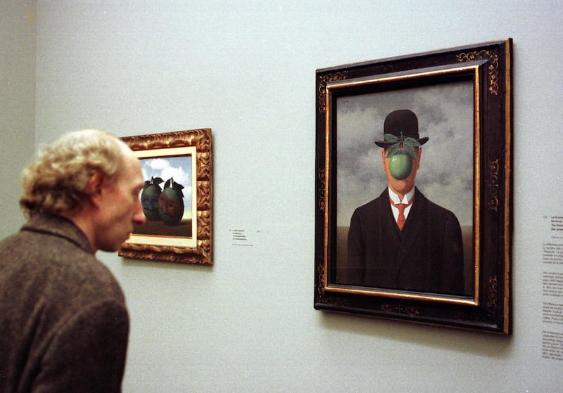 A man looks at the surrealistic painting "The Great War" during the Rene Magritte exhibition at the Brussels' Modern Art Museum 04 March. (Photo by HERWIG VERGULT / BELGA / AFP)