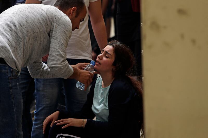A man gives a drink of water to a woman grieving at the entrance of the morgue. AFP