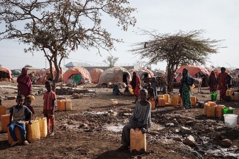 People wait for water with containers at a camp, in Baidoa. 