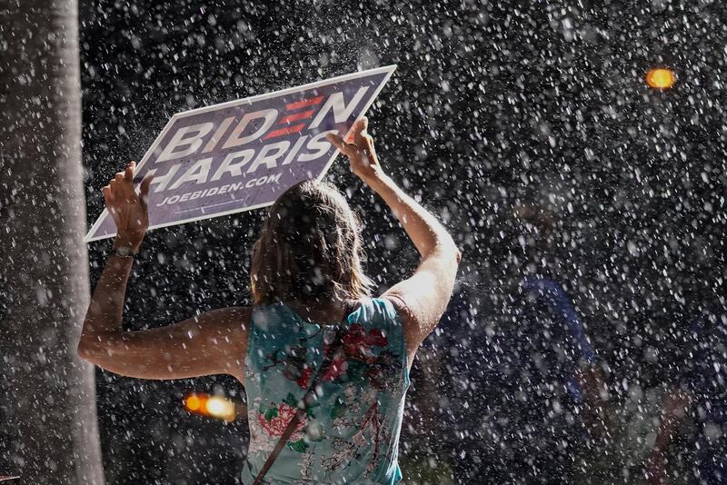 A Joe Biden supporter stands in the rain as the Democratic presidential candidate speaks at a drive-in rally at the Florida State Fairgrounds in Tampa on October 29, 2020. AP Photo