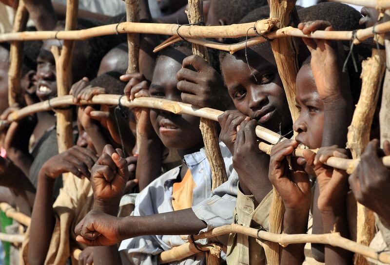 Sudanese refugee children press up against a fence in Djabal refugee camp near Goz Beida southern Chad on March 15, 2009. United Nations forces took over command from European Union peacekeepers here Sunday to protect refugees and displaced people in Chad and the Central African Republic.  The EU's EUFOR troops swapped their berets for the UN peacekeeping ones in in the eastern Chadian town of Abeche in a symbolic handover ceremony attended by senior officials and diplomats, including French Foreign Minister Bernard Kouchner. Some 5,200 peacekeepers from the UN's MINURCAT mission are now charged with protecting refugees from Sudan's strife-torn Darfur region and people displaced by a rebel insurgency in Chad and northern Central African Republic, though roughly 2,000 members of the European force will remain for a few more months under the UN beret until African and Nepalese units arrive. AFP PHOTO PHILIPPE HUGUEN (Photo by PHILIPPE HUGUEN / AFP)