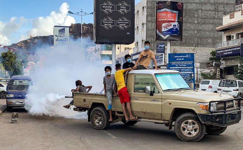 Youths wearing masks as a precaution due to COVID-19 coronavirus disease, sit in the back of a truck carrying out a fumigation in an area in Yemen's southern coastal city of Aden on May 5, 2020, as part of a campaign to prevent the spread of insect-borne diseases such as malaria, dengue fever, and Chikungunya virus amidst the novel coronavirus pandemic.  / AFP / Saleh Al-OBEIDI
