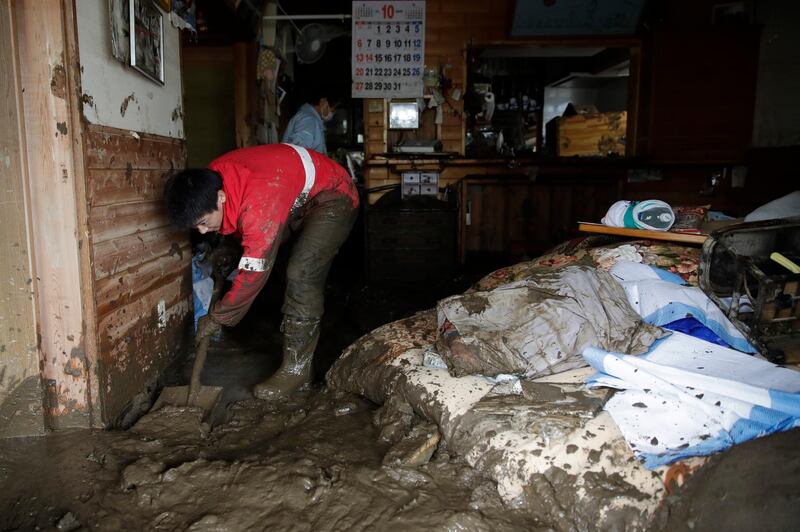 Yoshiki Yoshimura, 17, cleans up mud at his home after Typhoon Hagibis passed through the neighborhood in Nagano, Japan. More victims and more damage have been found in typhoon-hit areas of central and northern Japan, where rescue crews are searching for people still missing. (AP Photo/Jae C. Hong)