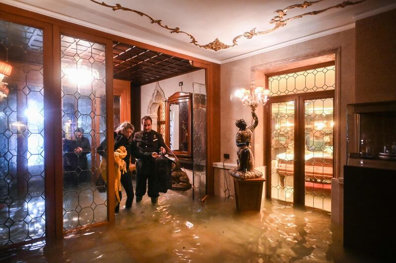 An employee of the Gritti Palace helps a customer walk across the flooded entrance. AFP