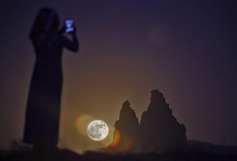 A woman takes a picture of the supermoon as it rises over the desert near Tabuk, some 1,500 kilometers northwest of the Saudi capital Riyad. Mohammed Albuhaisi / AFP