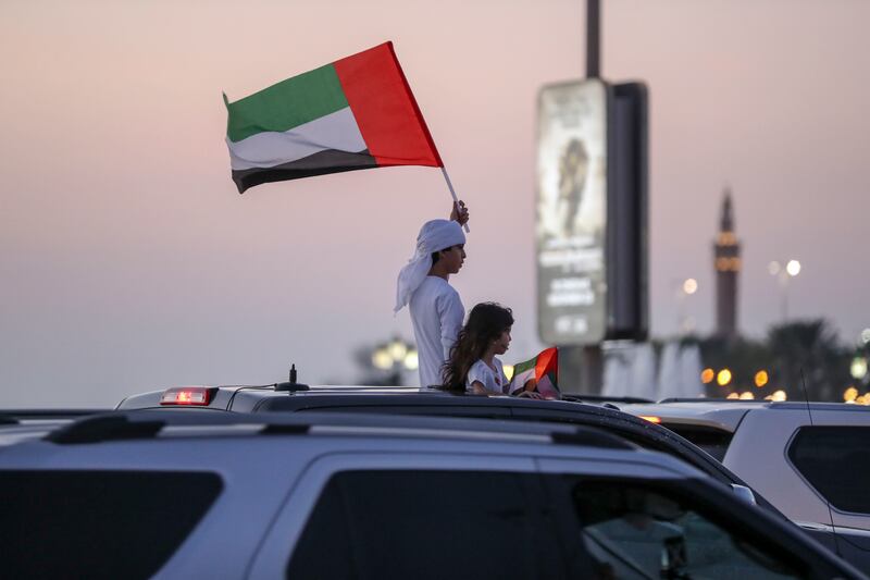 Proud Emirati children wave the UAE flag from their car's sunroof along the Corniche, Abu Dhabi in 2021. Khushnum Bhandari / The National 