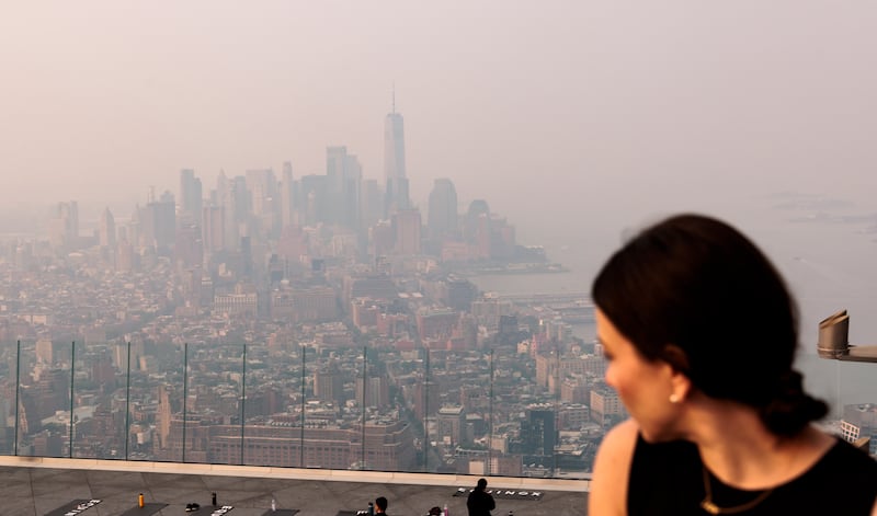 A woman looks at the Manhattan skyline engulfed in haze caused by smoke. EPA