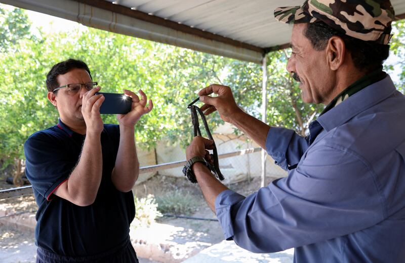 Bahraini Sayed Adnan films Yaseen as he explains how to handle a snake.