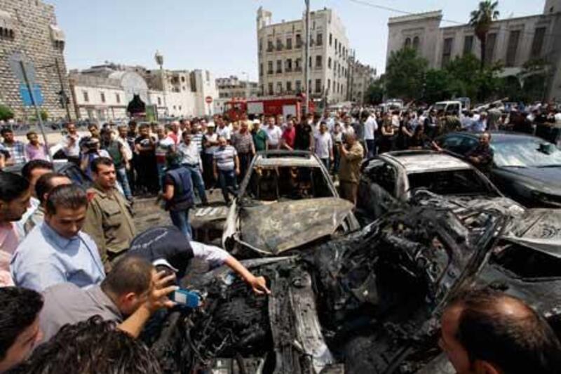 Syrians inspect burned cars at the site of a blast in the Syrian capital Damascus.