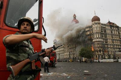 FILE - In this Nov. 29, 2008, file photo, an Indian soldier takes cover as the Taj Mahal hotel burns during gun battle between Indian military and militants inside the hotel in Mumbai, India. A Chicago businessman convicted of supporting terrorist groups has been arrested in Los Angeles to face charges in India for attacks in Mumbai in 2008 that killed more than 160 people. Federal prosecutors said Friday, June 19, 2020, that Tahawwur Rana, a Pakistani-born Canadian, was arrested after winning an early release from a Los Angeles federal prison because of coronavirus. (AP Photo/David Guttenfelder)