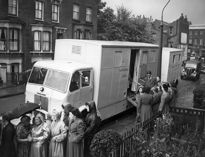 NHS patients queuing in the rain outside a mobile X-ray unit parked in a street in New Cross, London in 1954. Getty Images