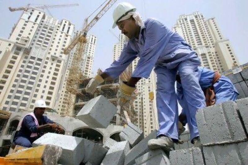 A worker unloads cement blocks from a truck at a construction site in Dubai. REUTERS / Devadasan