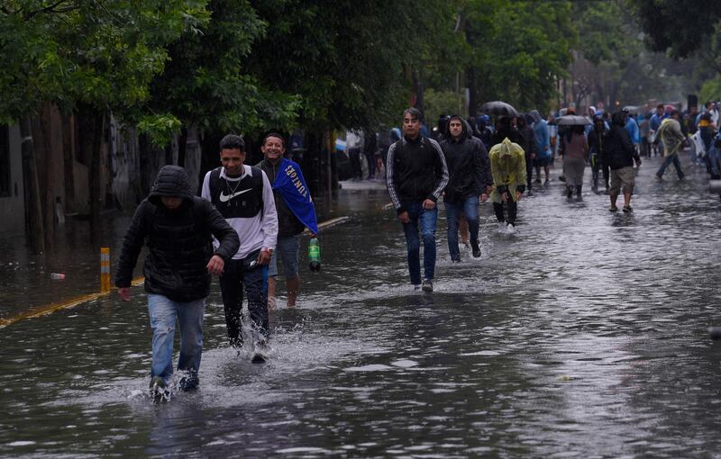 Fans make their way through flooded streets towards the stadium. AP Photo