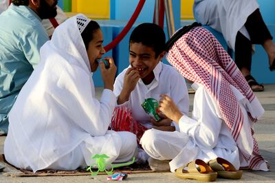 Saudi children wearing their new clothes eat sweets and play as they join adults performing Eid Al Fitr prayers at a mosque in Riyadh. EPA
