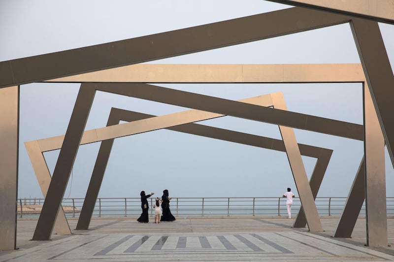 Women walk past an art installation on the corniche promenade in Dhahran, Saudi Arabia. Bloomberg