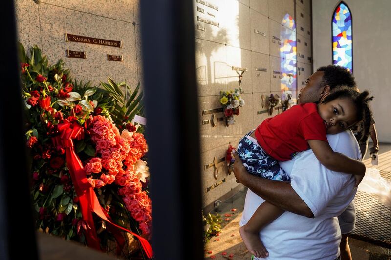 A mourner carries a child as he pays his respect. Reuters