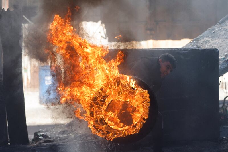 A Palestinian protester pushes a burning tyre during clashes in Hebron, in the Israeli-occupied West Bank. Reuters