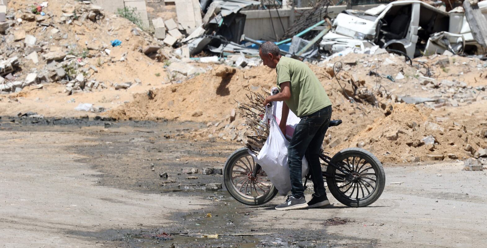 A Palestinian man pushes his bicycle in Beit Lahya in the northern Gaza Strip on May 4, 2024, amid the ongoing conflict between Israel and the militant group Hamas.  (Photo by AFP)