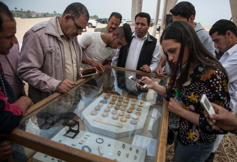 People look at miniature vessels and other objects found in the burial chamber. EPA