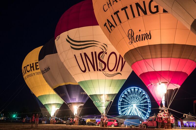 Crowds watch as tethered balloons are illuminated by their burners during the night glow evening event on the first day of the Bristol International Balloon Fiesta. Getty Images