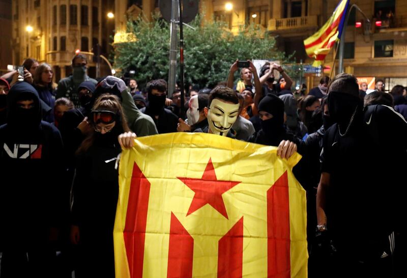 A masked Catalan pro-independence demonstrator holds an Estelada (Catalan separatist flag) during a protest against police action, outside the National Police headquarters, in Barcelona, Spain, October 26, 2019. REUTERS/Sergio Perez