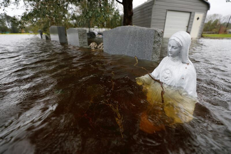 A Christian statuette is partially submerged in rising flood waters inundating a cemetery in the aftermath of Hurricane Florence, in Leland, North Carolina. Reuters