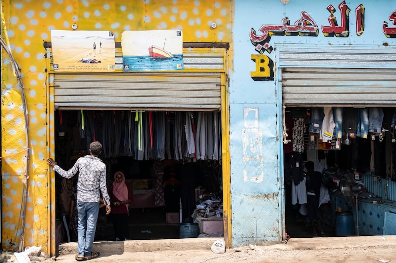 An Eritrean youth peers into a clothes shop in the market at Shagarab refugee camp, which hosts more than 60,000 people, in Sudan. On its walls are signs from the UN warning residents about the dangers of following migration routes through deserts and across seas. Getty