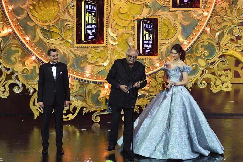 Bollywood film producer Boney Kapoor (C) receives the award for best performance in a leading role - female in behalf of his late wife and actress Sridevi for her role in "Mom" while Bollywood actress Kriti Sanon (R) and Tarun Garg (L) executive director Maruti Suzuki and executive vice president of Nexa looks on during the IIFA Awards of the 19th International Indian Film Academy (IIFA) festival at the Siam Niramit Theatre in Bangkok on June 24, 2018. / AFP / INDRANIL MUKHERJEE
