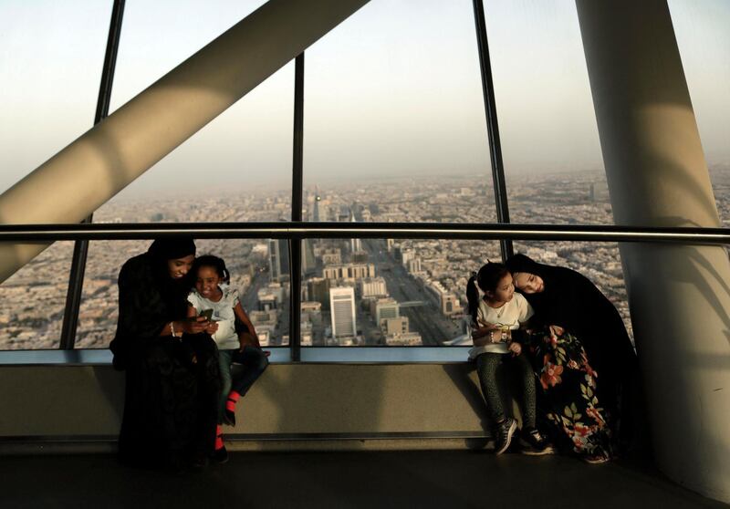 FILE - In this June 23, 2018 file photo, women hold their daughters as they visit the Four Seasons Skyline Tower, in Riyadh, Saudi Arabia. King Salman has extended monthly allowances for government employees, military personnel, pensioners, social security recipients and students into next year. The announcement, carried by the Saudi Press Agency on Tuesday, Dec. 18, 2018, comes on the same day the kingdom's 2019 budget is scheduled to be unveiled. (AP Photo/Nariman El-Mofty, File)